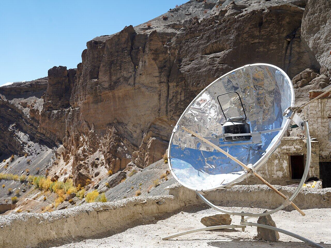 Parabolic solar cooker focusing sunlight on a pot